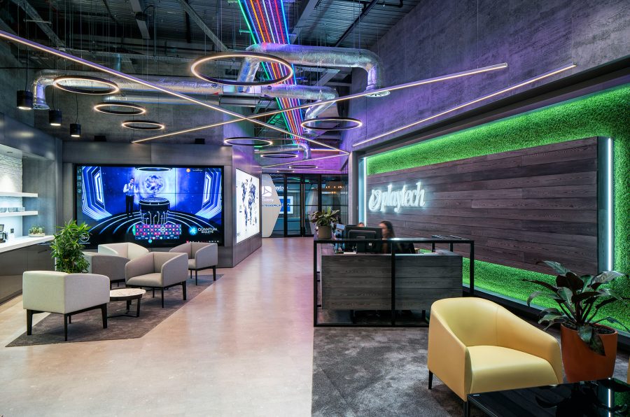Industrial interior design for Playtech reception, decorated with coloured way finding LED lights, minimal furniture design and opulent carpet.