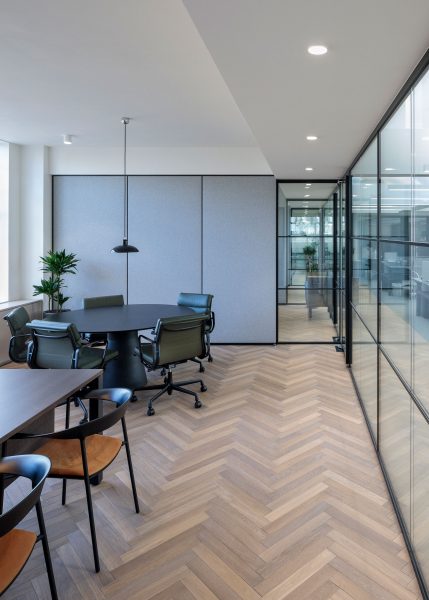 Meeting room designed with parquet floor tiles and glazed partitions.
