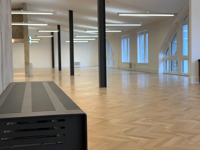 Exposed black steel beams and air conditioning black cabinets create a modern industrial style look for this office space, near London.