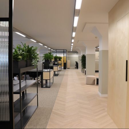 Plug and play scheme in a workplace decorated with neutral parquet flooring, open plan workspace and wooden storage wall.