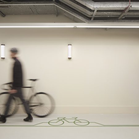 A man walking with a bike into a office wellness space.