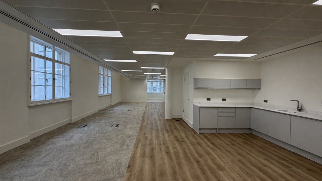 An office space with a grey new kitchen laminated floors and carpet tiles
